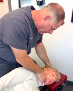 Dr. Packer adjustment v2 (4x5) Dr. David Packer holding a patient's head to perform a NUCCA chiropractic adjustment