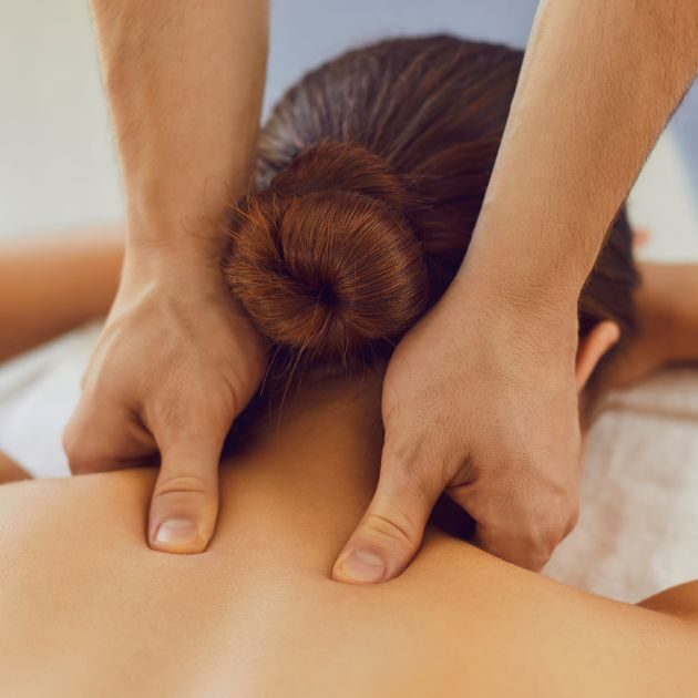 massage therapist performing deep tissue massage on a patient's upper back