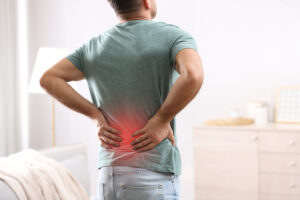 Man suffering from back pain at home. Bad posture problem Man holding his lower back with red highlight indicating area of back pain